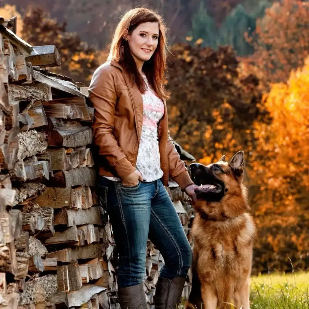 Woman standing with her German Shepherd in an autumn setting, illustrating the deep companionship and loyalty between protection dogs and their owners